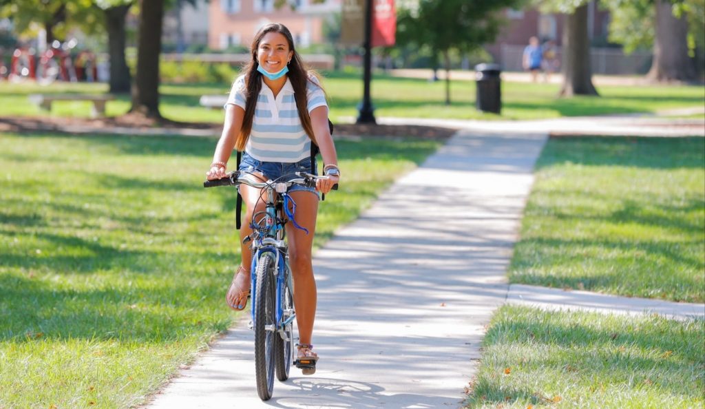 A girl on a bicycle rides through Bridgewater College's campus on the first day of classes 2021