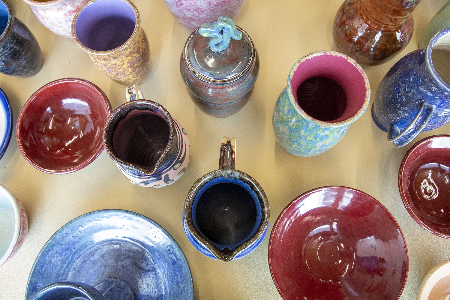 a photo of colorful pottery taken from above with a view inside the cups and mugs